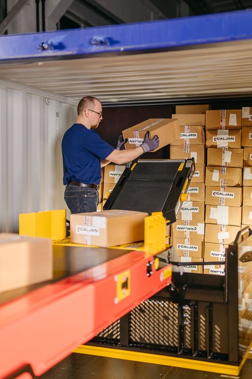 Operator using Caljan ErgoRider to ergonomically unload packages from a high point in trailer