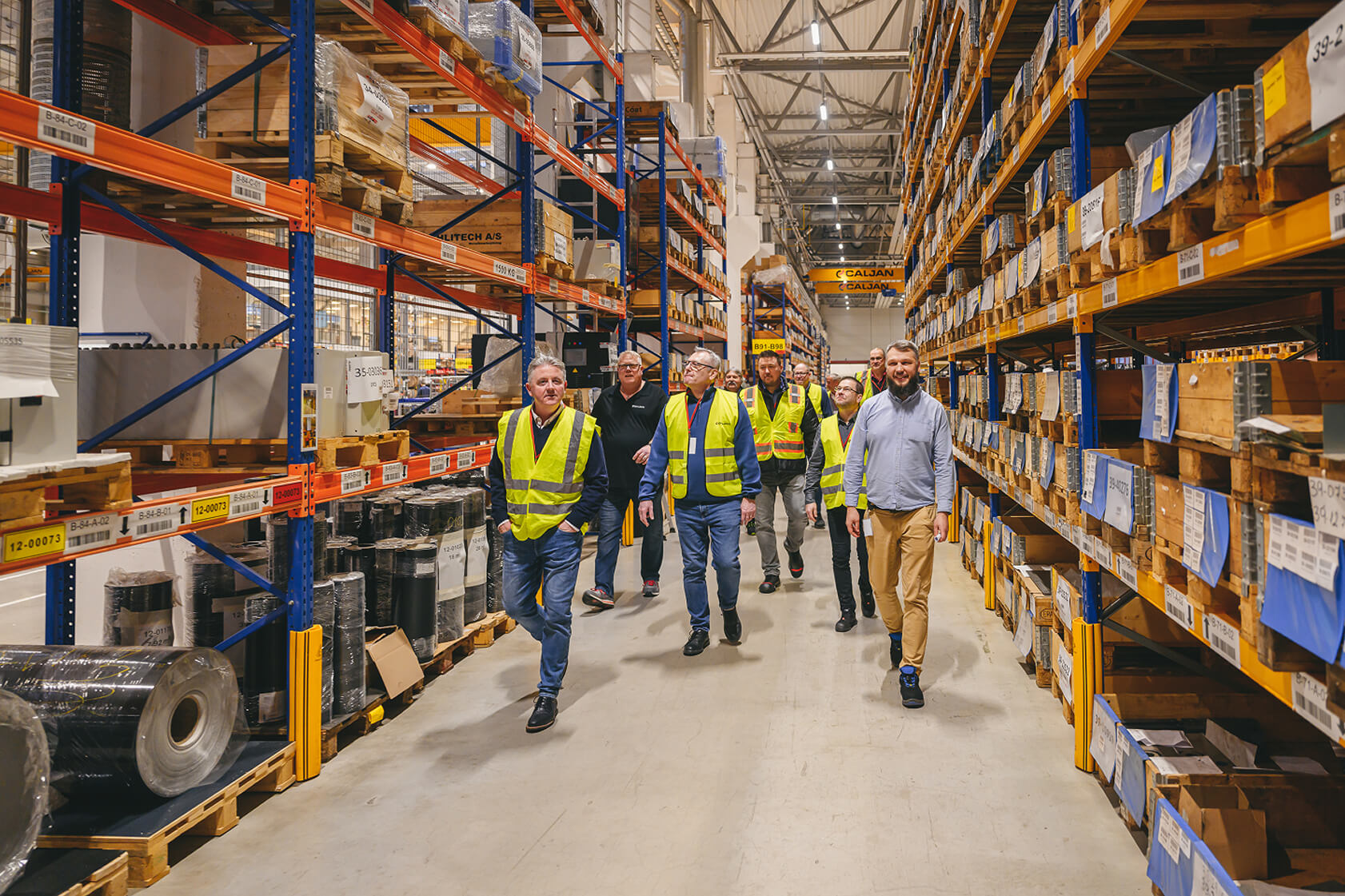 group of people walking in Caljan Latvia production warehouse