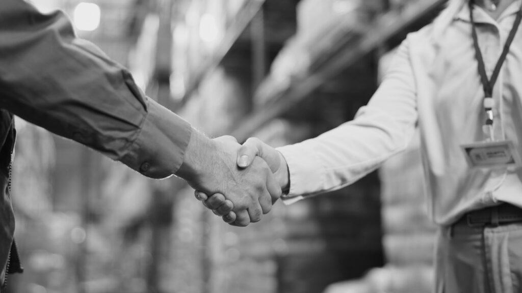 Poignée de main de deux personnes dans un entrepôt, rencontre et accord pour la chaîne d'approvisionnement